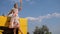 Rural girl into dress Waving of Hand standing on bonnet of tractor at nature on background of sky