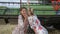 Rural girl in dress whispering Gossips of Girlfriend in ear on field near Combine harvester