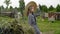 Rural girl in hat posing on haystack and hayfork background in countryside. Rustic teen girl on dry hayrick and