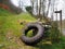 Rural grass covered track leading up hill with a wooden direction sign and an old moss covered tyre leaning on a stone wall