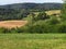 Rural hilly landscape, country with green meadow in summer, plowed field, Czech republic