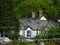 A rural house in the Lake District with white walls, grey slate roof and two chimneys