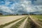 Rural landscape with fields, dirt road and clouds in the sky