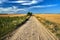 Rural landscape with Granite cobblestones road between arable fields after the harvest