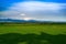 Rural landscape with green fields to the horizon. Against the background of the Caucasus Mountains in the haze and blue sky with