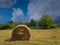 Rural landscape with hay stacks, field with roll bales near forest, domestic livestock fodder during wintertime