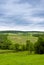 Rural landscape. Hilly terrain. Forest fields and cloudy skies with clouds.