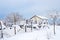 Rural landscape. House with a fence covered with snow on a winter day. Abundant snowfalls