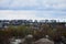 A rural landscape with many private houses and green trees. Suburban panorama on a cloudy afternoon. A place far from the cit