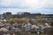 A rural landscape with many private houses and green trees. Suburban panorama on a cloudy afternoon. A place far from the cit