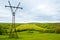 Rural landscape. Power line tower on hilly terrain. Forest fields and cloudy skies with clouds.