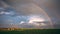 Rural landscape, rain clouds and rainbow, time-lapse.
