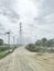 rural landscape  Signal antennas paired with towering electricity poles  The daytime sky is white alternating with gray clouds.