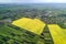 Rural landscape on spring or summer day. Aerial view of green, plowed and blooming fields, house roofs on sunny dawn. Drone