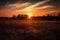 rural landscape with sun setting behind the horizon, casting warm colors across the sky