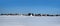 Rural landscape with a village on skyline after snow field under clear blue cloudless sky on bright sunny day panoramic view