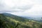 Rural mountain view with cloudy sky and hilly jungle. Green hilltop view with a drone. Hiking trail landscape photograph of hills