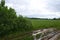 Rural muddy dirt road in summer after rain on the background of green bushes.