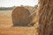 Rural nature in farmlands. Golden hey bale in the field. Yellow straw stacked in a roll. Wheat harvest in the summer