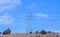 Rural Overhead Power Line Grid Against Blue Cloudy Sky