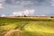 Rural pastoral landscape with green grass fields and white clouds sky.