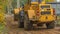 Rural road construction with grader in autumn daytime. The grader repairs the dirt road in the village.