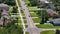 Rural road with driving traffic cars in American small town in Florida. Private homes between green trees and suburban