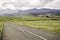 A rural road leading into the Drakensburg mountains in the distance