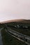 Rural road winding through a picturesque landscape, featuring a fenced-in area