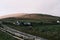 Rural road winding through a picturesque landscape, featuring a fenced-in area