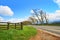 Rural road, wooden fence and blue sky