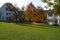 Rural scene in autumn. Residential building and school with colorful autumn trees in the background.