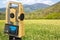 Rural scene with field and 3D rendering of a geodesic device, called Total Station used for the survey of topographic maps and