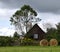 Rural summer landscape in Carpathian Mountains, green meadow, old house