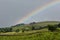 A rural UK countryside scene with a stormy sky and a rainbow spanning the sky