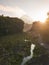 Rural view of river and lava path surrounded by dense of forest with mountain background and blue sky in sunrise time