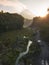 Rural view of river and lava path surrounded by dense of forest with mountain background and blue sky in sunrise time