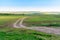 Rural winding road extending beyond the horizon. Fresh spring grass in the fields and meadows on a sunny day. Beautiful landscape