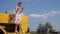 Rural woman photographed to phone on hood of combine harvester on nature