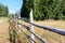 Rural wooden fence with barbed wire, dry grass is on field at summer season