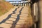 Rural wooden fence with shadow on unpaved sand path