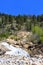 A rushing waterfall, Adams Falls, on a rocky mountain slope in the midst of a forest in Rocky Mountain National Park