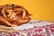 Rushnyk with korovai, wheat spikes on yellow background, closeup. Ukrainian bread and salt welcoming tradition