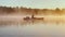 Russia, Karelia, 06 July 2021: Kayaker floats on calm water through the morning fog above the water at sunrise, the