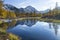 Russia. Magadan Region. A beautiful forest lake against the backdrop of the Big Anngachak mountain range. Autumn in the vicinity