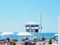 Russia, Sochi 28.06.2020. A striped white-blue rescue tower stands in the middle of the beach with white umbrellas