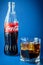 Russia, St. Petersburg, February 2020: an open bottle of the world`s most popular drink Coca-Cola on a classic blue background