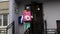 Russia, St. Petersburg - June 2020. Courier approaches the porch. Food delivery man in a street with pink bag box for food.