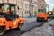 RUSSIA, ST.PETERSBURG - MAY 12, 2019: Repair of roads. Three orange asphalt pavers and workers in orange-gray coveralls