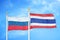 Russia and Thailand two flags on flagpoles and blue cloudy sky